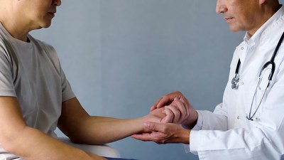 Doctor examining Asian man's wrist