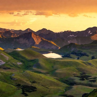 Sunset over green alpine mountains lake