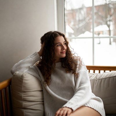 Woman with curly hair gazing out snowy window