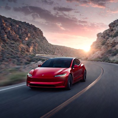 Red Tesla driving mountain road sunset