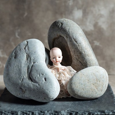 Porcelain Doll Between Large Rocks