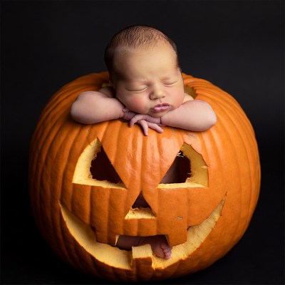 Newborn baby sleeping in jack-o-lantern pumpkin