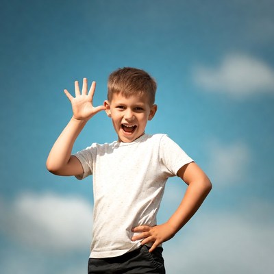 Boy waving hand on blue sky