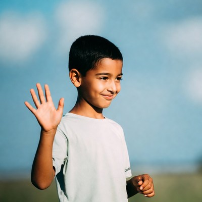 Young boy waving happily outdoors