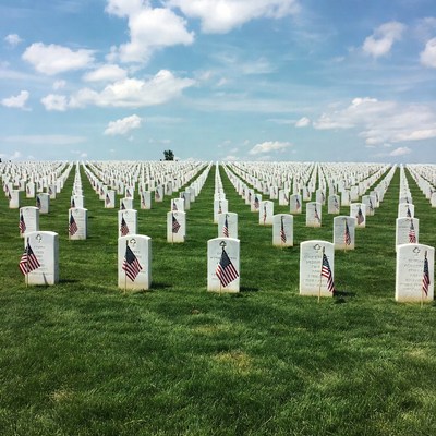 American flags on gravestones in cemetery