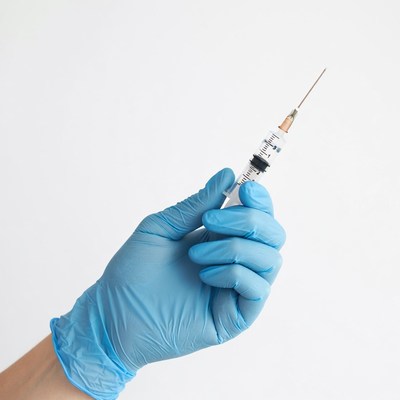 Hand holding syringe in blue glove