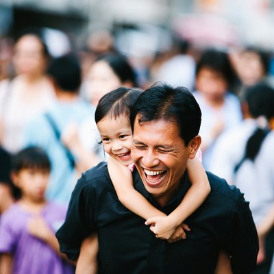Asian father piggybacking smiling daughter