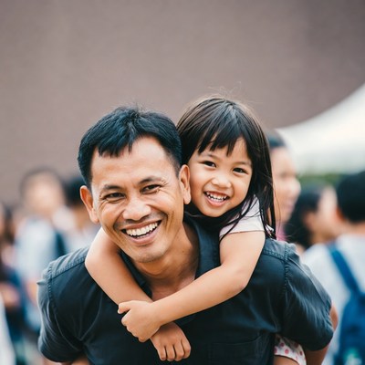 Asian father piggybacking smiling daughter