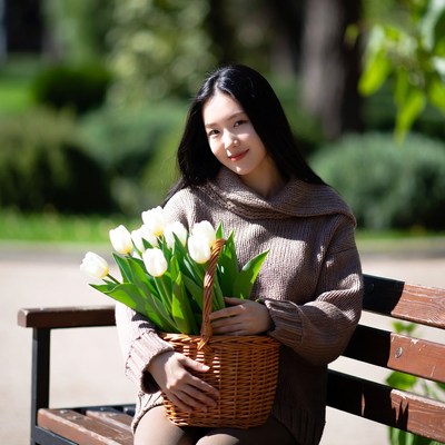 Asian woman holding tulips on bench