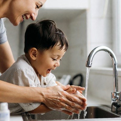 Mother helping toddler wash hands