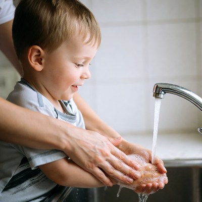 Mother helping toddler wash hands