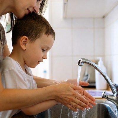 Mother helping boy wash hands