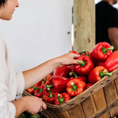 Asian woman selecting red peppers at market