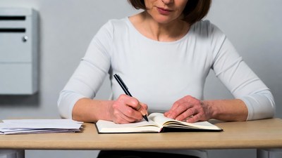 Mature woman writing in notebook