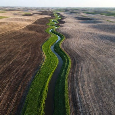 Winding green river through farmland fields