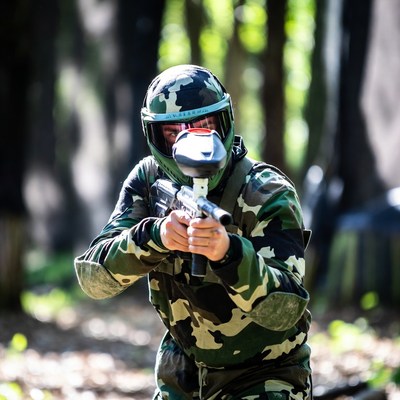 Man aiming paintball gun in forest