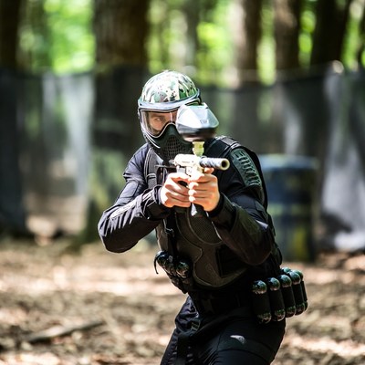 Man aiming paintball gun in forest