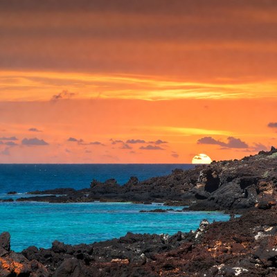 Sunset over black lava rocks and ocean