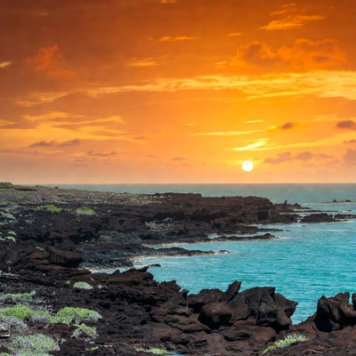 Sunset over black lava rocks and ocean