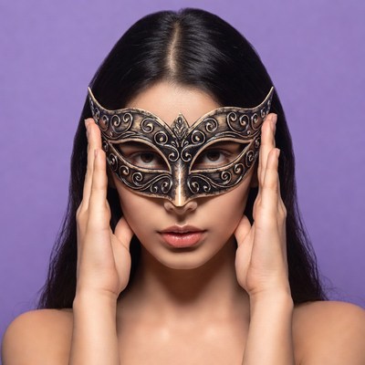 Asian woman holding ornate masquerade mask