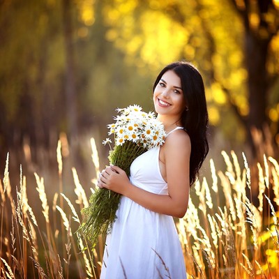 Woman holding daisies in autumn field