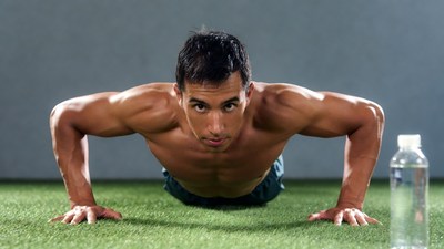 Muscular man doing pushups on grass
