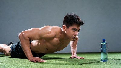 Asian man doing pushups on gym mat