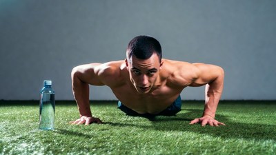 Muscular man doing pushups on grass