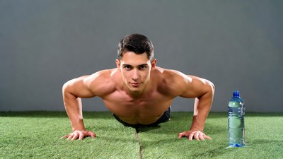 Muscular man doing pushups on grass