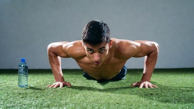 Muscular man doing pushups on grass