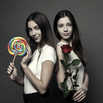 Two girls holding lollipop and rose