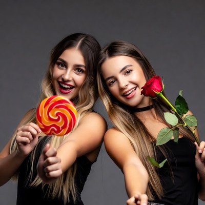 Two women holding lollipop and rose