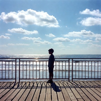 Boy leaning on pier railing at sunset