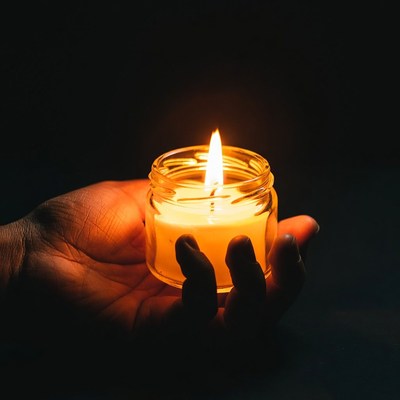 Hand holding lit jar candle