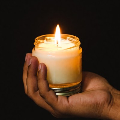 Hand holding lit candle