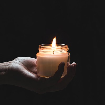 Hand holding lit jar candle