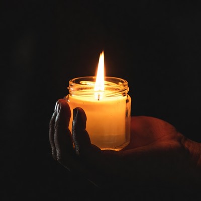 Hand holding lit jar candle