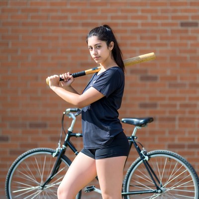 Girl holding bat by bicycle