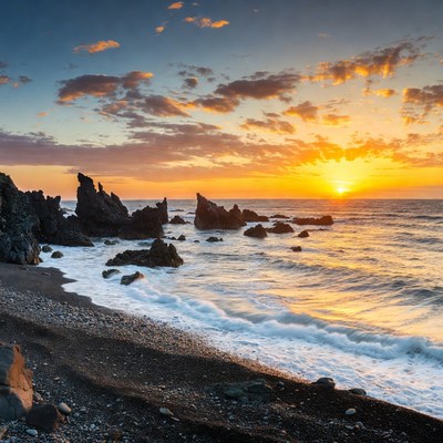 Sunset over rocky black sand beach
