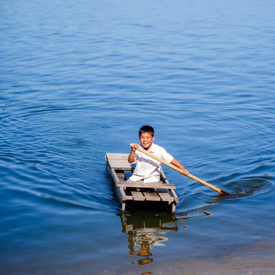 Asian boy rowing wooden boat