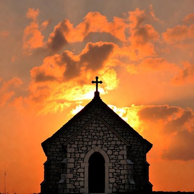 Stone chapel silhouetted against sunset