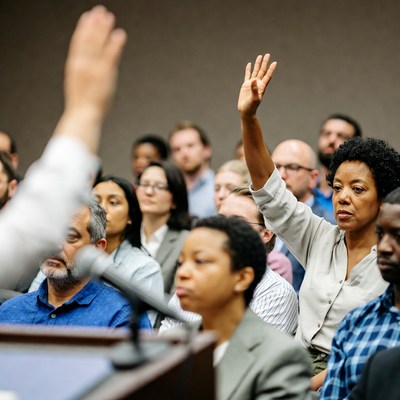 African-American woman raising hand in meeting