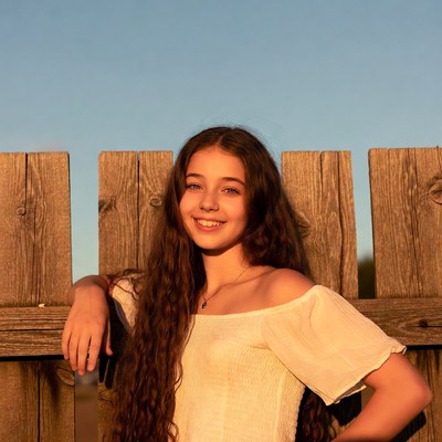 Teen girl smiling by wooden fence