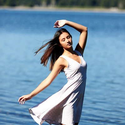 Woman dancing by lake in white dress
