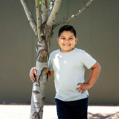 Young Latino boy leaning on tree