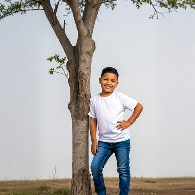 Young Latino boy leaning against tree