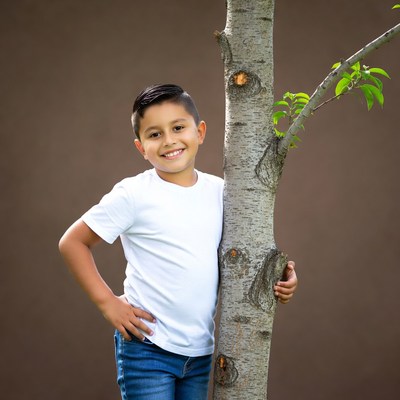 Smiling Latino boy leaning on tree