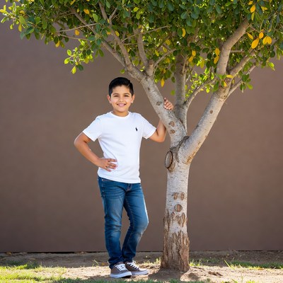 Latino boy leaning on tree