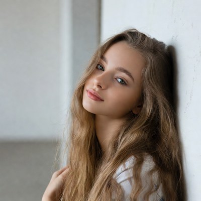 Teen girl leaning against white wall