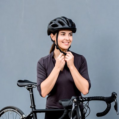 Woman adjusting helmet beside bike